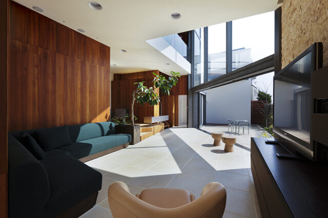 Sさんが選んだソファーが、この家のベストポジションに鎮座。テレビ横の壁は、石板をSさんが自ら１枚１枚並べたという。
