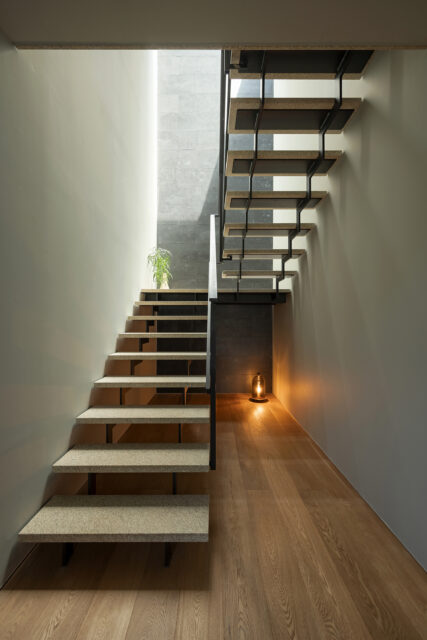 1階階段。踏板には石材を張った。２階上部にトップライトを計画。家の奥に当たる部分だが十分明るい