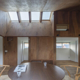 明るい天窓や最大約4mの高さがある勾配天井が開放感を演出。内装も工夫し、ダイニングは木、周囲の空間は白壁と、内装カラーにメリハリをつけて奥行きを強調した。さらには全ての方角に窓を設けて視線の抜けを確保。多層的な工夫により「広く感じる空間」を実現している