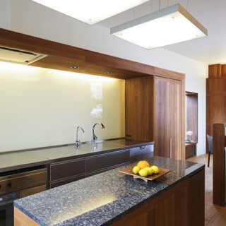 キッチンは回遊できるアイランド型。天板はステンレスのバイブレーション仕上げ。壁パネルは強化ガラスを使うことで清潔感と掃除のしやすさを求めた。
