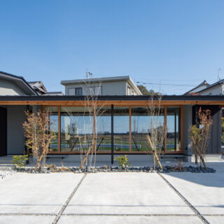 外観（西側正面）。景観が良い西側を大きく開き、そこにLDKを配した（写真中央）。L字型の平屋とし、写真左のエリアには寝室や水回り、子供部屋や収納スペースを集中的に配置。効率的な導線となるプランとした。平屋としたことで、背後の家からも田園風景を眺めることができる