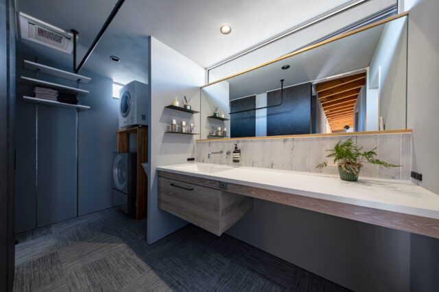 水回り。洗面台は広さを重視し、効率的な家事動線にも気を配った。奥の洗濯機・乾燥機と洗面台の間には、スロップシンクも設置されている。北側に位置するが、洗面台の幅と同じ長さのハイサイドライトにより、十分な明るさを確保している
