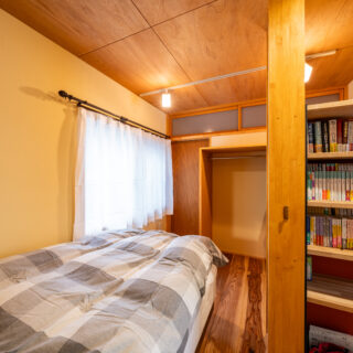 奥さまの個室。右に配置されている和室との仕切りはカーテンとした。開放してもL字の棚のおかげで中は見えにくい。窓は二重窓に変更し、また壁の内部にも断熱材を入れ断熱性能を上げた。上部に欄間のある壁面の裏にご主人の個室があり、壁面左の扉から行き来できる