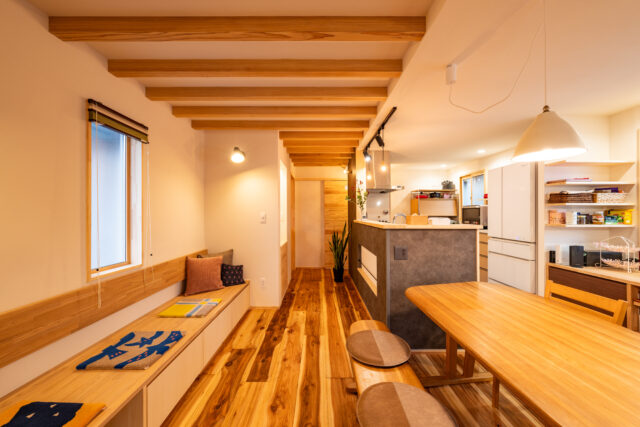 ヌック側からLDKを見通す。ご要望から壁際の下部に収納付きのベンチを造作した。以前の壁はクロス張りだったが、クロスの上から漆喰を塗り自然素材の空気感に満ちた空間を実現。そのうえでベンチには「漆喰に背中を付けるのもあまりよくないので」と木材の背もたれも設置した