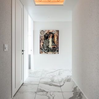 絵とのマッチングを考慮し光天井を採用し、ひし形模様のファブリックで仕上げた。壁には壁紙の上からジョリパットを塗り、光が当たるたびに陰影が生まれる。絵を引き立てるための舞台装置のような玄関だ。