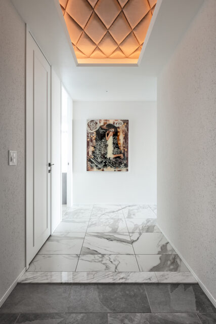 絵とのマッチングを考慮し光天井を採用し、ひし形模様のファブリックで仕上げた。壁には壁紙の上からジョリパットを塗り、光が当たるたびに陰影が生まれる。絵を引き立てるための舞台装置のような玄関だ。