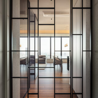 グリッド状の桟が印象的な扉。グレーのガラスが、窓先の景色まで見渡せる抜け感と、玄関が見えない実用性を両立。