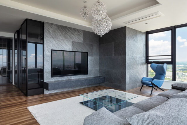 書斎とリビングを分ける壁は新たに施工し、その中にテレビを埋め込み配線などを隠蔽した。表面にはわずか1.5㎜の厚さの石を貼ることで、自然な風合を表現。