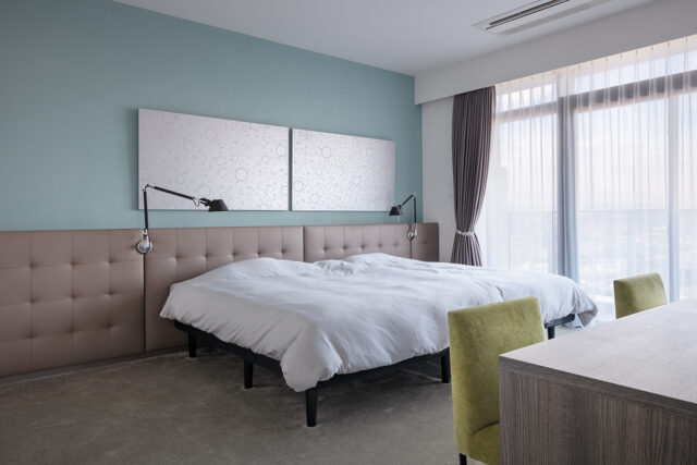 寝室はホテルライクなカーペットで。銀色のアートに合うように、壁はセージグリーン、ヘッドボードはグレージュとし、寒色と暖色でバランスをとりくすみカラーで統一した。