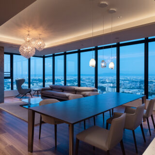 パノラマビューなリビング。建ち並ぶビルやマンションを見下ろし、遠くの山並みまで見渡せる圧倒的な開放感。夜になれば無数の灯りが瞬く幻想的な夜景が広がる。