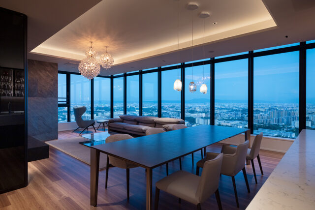 パノラマビューなリビング。建ち並ぶビルやマンションを見下ろし、遠くの山並みまで見渡せる圧倒的な開放感。夜になれば無数の灯りが瞬く幻想的な夜景が広がる。