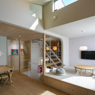 リビングのソファスペースは塔屋階までの吹抜けで、抜群の開放感。上部にはトップサイドライトもあり青空が見える。小上がりの階段を上った先は屋上へ出る塔屋階