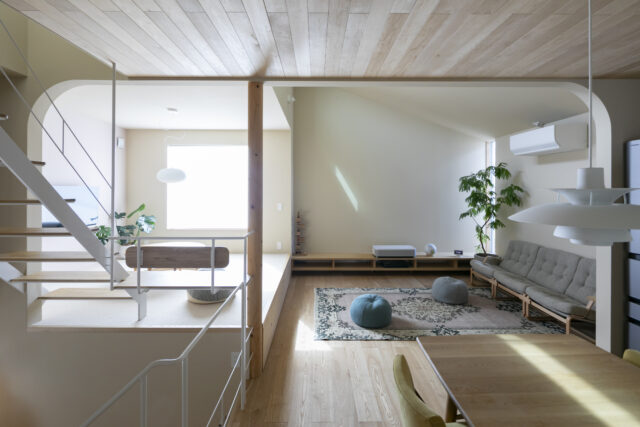 ダイニングからリビングを見る。リビングにはソファスペースと小上がりがあり、小上がりでは子どもが床座でおもちゃ遊びなどを楽しめる。一方のソファスペースは大人が落ち着ける雰囲気。写真正面の壁には、プロジェクターで映画などを映すこともできる