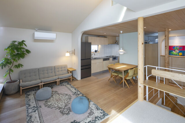 2階LDK。北側（写真右）がキッチン・ダイニング、南側（写真左）がリビングで、下がり壁や丸柱でそれとなくゾーニングされている。壁は空間ごとにアクセントカラーをプラス。ダイニングはグリーンだがとても淡い色調で、ナチュラルな雰囲気を損なわずに明るさ・楽しさを演出