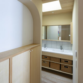 飾り棚もアールをつけて柔らかな印象に。タイルでデザイン性を高めた洗面室はシンクが2つあって便利