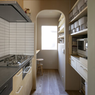 キッチン。リビングなどから見えない位置にオープン収納を設置。奥にはデスクワークができるパントリーも