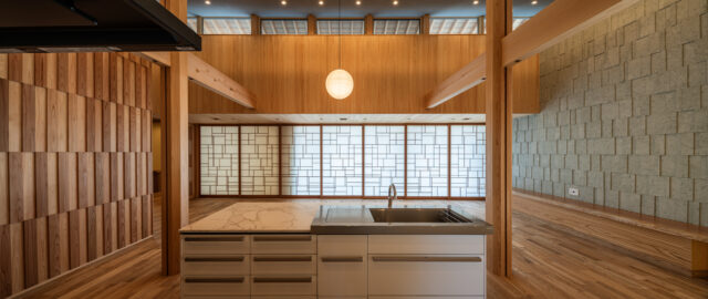 キッチン奥から見た庭方向。左右の壁の質感の違いと造作の飾り障子の美しさを楽しむことができる。障子の模様は、右側にある十和田石の壁と調和するデザインとした。全体的に木材に囲われ、安らぎと安心感を感じる
