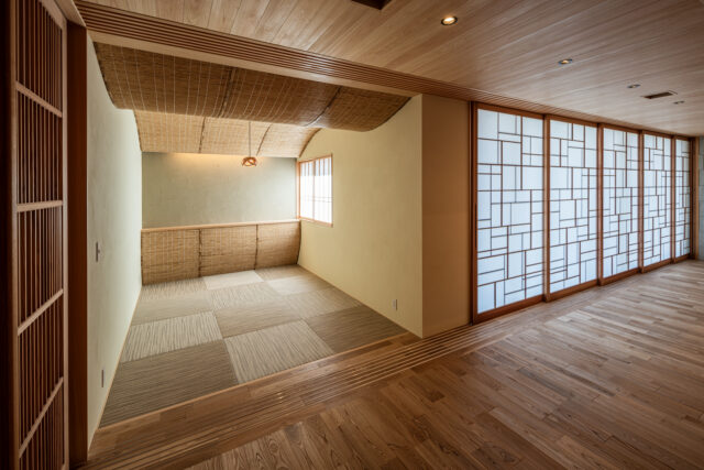 LDKに接した和室。お施主様から自由にやってほしいと言われ、曲線を多用した遊び心ある空間に。天井と奥の腰壁に葦を使用し、柔らかな空間とした。庭側の障子を和室の前まで動かし、閉ざすこともできる