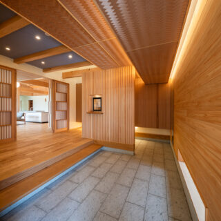 長い奥行きの玄関。檜の壁、十和田石の床、網代天井など、素材の美しさを感じられる空間となっている
