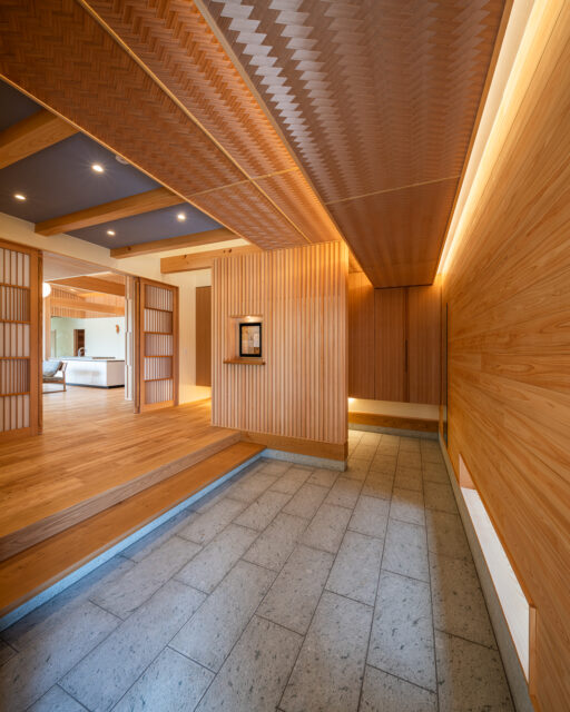 長い奥行きの玄関。檜の壁、十和田石の床、網代天井など、素材の美しさを感じられる空間となっている