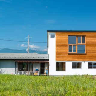 ご実家の敷地内、ご両親が住まう平屋に寄り添うように建てられた狭小2階建て。休耕田が広がる東側の開けた眺めを借景として取り入れるため、2階LDKに大きな窓を設けている