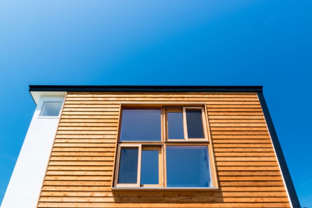 レッドシダーの鎧張りの外壁は、下から上に斜めにハングする（せり上がる）造り。上部の窓枠に奥行きが生まれ、庇として機能し、雨水などによる木製窓の劣化を防いでくれる効果も