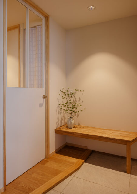 以前より面積を拡大し柔らかく温もりある玄関に。片隅には、木製ベンチを配置。ちょっとした荷物置きや靴の脱ぎ履きに重宝する。