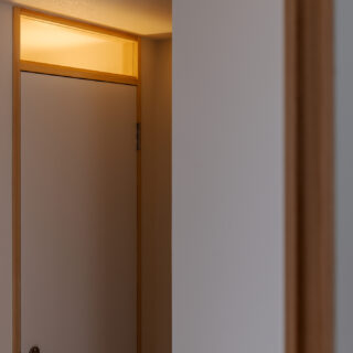 トイレの扉の上部は在室がわかるようガラスに。この奥に、キッチンへと回遊できるクローゼットを設置。日常使いの道具の収納やパントリーとして重宝するスペースだ。