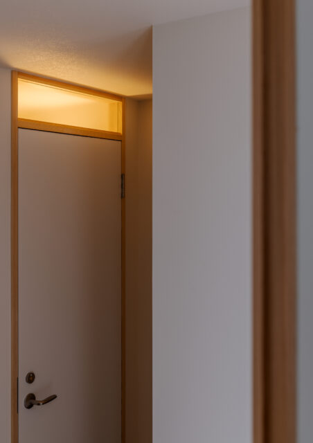 トイレの扉の上部は在室がわかるようガラスに。この奥に、キッチンへと回遊できるクローゼットを設置。日常使いの道具の収納やパントリーとして重宝するスペースだ。