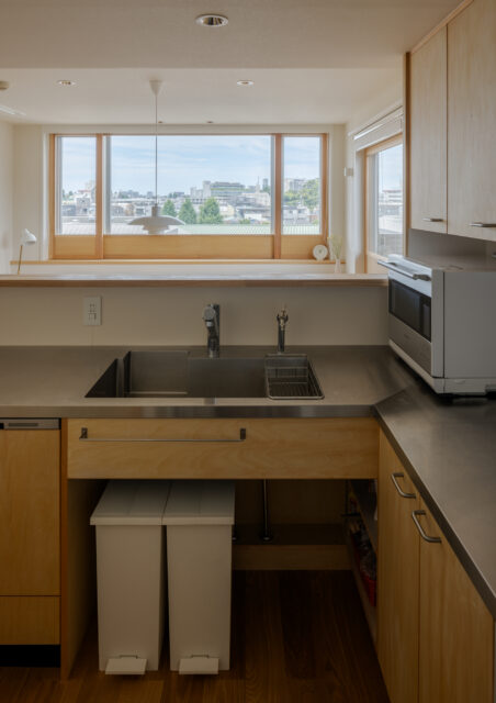 オープンなキッチンとしたことで、作業をしながら遠くの景色を楽しめる。回遊動線で使い勝手も良い。キッチンはIHや食洗器を仕込んだ造作のオリジナル。手元の雑然としたものをダイニングに見せないよう、カウンターを立ち上げている。