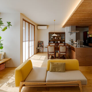 キッチンは天井高が2.2mで板張り。一方のリビングダイニングは、天井高が2.4ｍ。わずか20cmの差だが、視覚的にメリハリをつけることで、リビングダイニングに数字以上の開放感をもたらしている。ダイニングの奥には、想い出のアンティークの棚を設置した。