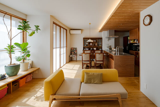 キッチンは天井高が2.2mで板張り。一方のリビングダイニングは、天井高が2.4ｍ。わずか20cmの差だが、視覚的にメリハリをつけることで、リビングダイニングに数字以上の開放感をもたらしている。ダイニングの奥には、想い出のアンティークの棚を設置した。