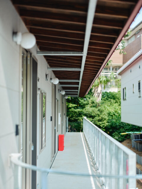 共用通路。雨天時にうれしい深い庇は上部の鉄骨で支えている。おかげで柱を立てずに済み、通路はすっきり