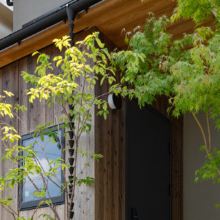 ジューンベリーやイロハモミジ、クロモジなど、四季折々で様々な表情をみせてくれる植栽を配し、訪れる人を出迎えてくれる。雨樋はデザイン性のある鎖樋を採用。雨が伝っていく様子がヌックの窓からも楽しめるようにとの配慮。