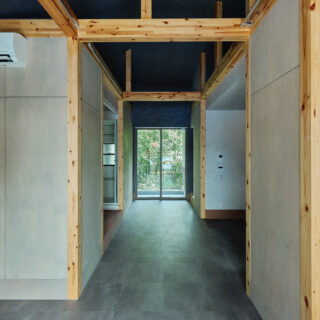 庭棟の住戸。玄関を入るとシックな通り土間の先に明るい緑が見え、思わず笑顔になってしまう。キッチンと個室を仕切る建具は（写真右）、緑と引き立て合う赤をセレクト。どの住戸も、差し色としてところどころに赤を入れている