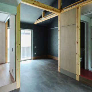 庭棟住戸のキッチンから玄関（写真奥）を見る。玄関土間は小商いの店舗利用を想定しているため、どの住戸も一般的な玄関ドアではなく中が見える窓サッシを入れている。住宅っぽくないオープンな佇まいが道行く人に注目され、施工期間中は「何ができるんだろう？」と話題に