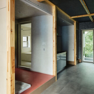 森棟の住戸。通り土間沿いに水まわりが並び、さらに奥にはインナーバルコニーに面した個室がある。水まわりなどのプライベートゾーンは入口の木枠を見せ、垂れ壁も少し奥に凹ませて額縁感を演出。パブリックゾーンの通り土間とは異なる空間であることを表現した