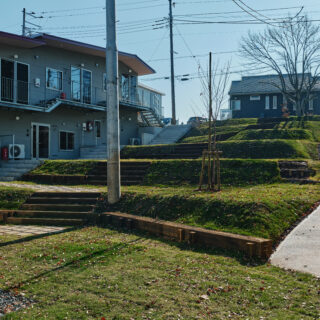斜面はもともとの地形を生かし、ひな壇状に整地。平らにならすよりも土の掘削量が少なくて済むというメリットもある。写真左の山棟も、傾斜のある地形に素直に従ったデザイン。屋根や通路が山脈のようなラインを描いているのが面白い