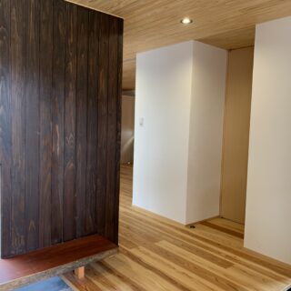 玄関ホール。中庭に面している壁はすべて杉板とし、アクセントに。その他の室内壁はしっくい。床は杉板のうずくりとした。自然素材を多用することで、メンテナンスが容易になり、家への愛着が湧く