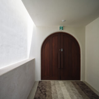 エントランスから入ってすぐの玄関ホール。アーチ型の両開きドアが印象的だ。トップライトから日差しが差し込み、季節や時間帯によってさまざまな陰影を生み出す。水廻りを除く室内の壁は、沖縄の漆喰で仕上げている