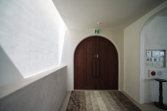 エントランスから入ってすぐの玄関ホール。アーチ型の両開きドアが印象的だ。トップライトから日差しが差し込み、季節や時間帯によってさまざまな陰影を生み出す。水廻りを除く室内の壁は、沖縄の漆喰で仕上げている