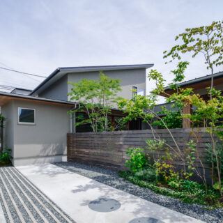 外壁は質感や耐候性に優れた塗装剤の左官塗り。中庭は木塀で覆いプライバシーを確保した。植栽は生活スペースが隠れるように、玄関（写真左奥）、庭の入口、庭の奥と、敷地の外側から奥に向かってバランス良く配置。人目を遮ると共に奥行きが強調され、空間の豊かさを感じられる