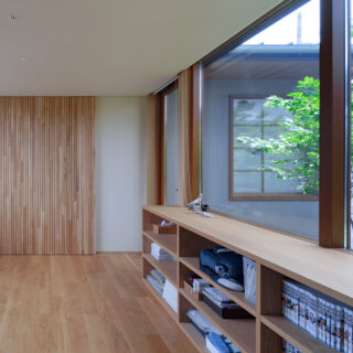 フリースペースには細いタモ材を張った壁面も。縦格子のデザインウォールかと思いきや、実はここには主寝室、納戸に続く2つの隠し扉がある。ドアノブや手掛けがないので空間がすっきりし、洗練された印象。心理的にも開けにくく、プライバシーを守ることにもつながっている