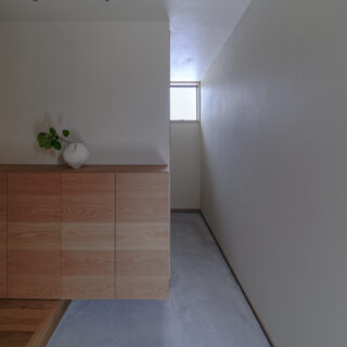 玄関土間。窓から入る光で漆喰壁の質感が際立つ。奥はキャンプ用品などをしまえる土間収納