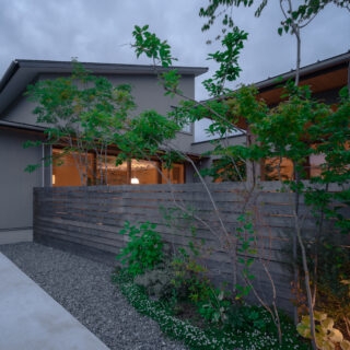 外観夕景。ほんのりとした優しい明かりが家族の幸せな時間を想像させる。自然が好きなHさん夫妻がこまめに手入れをしているという植栽は、街並みにも緑の癒やしをプレゼント