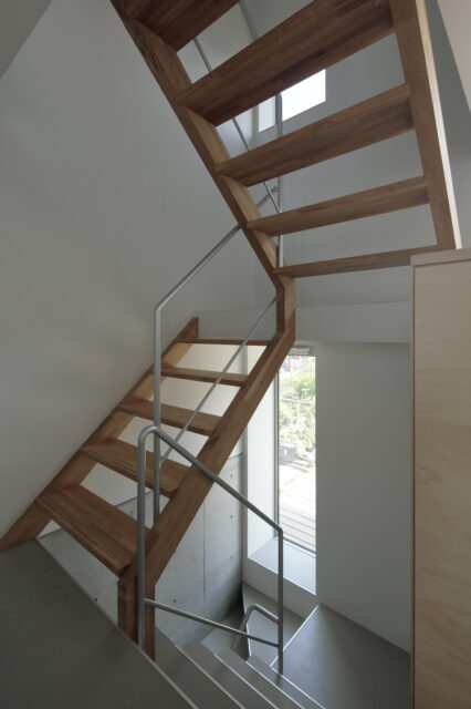 小さな建物の南側は階段スペース。１階から２階は箱階段、それより上は木製のスケルトン階段を採用し、上階からの光を降ろしている。