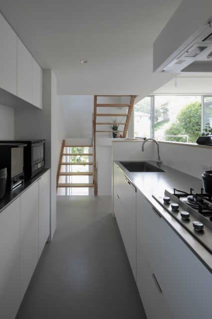 リビングダイニングを見渡せ、その先の景色も楽しめるキッチンは直線的な配置。高圧メラミンを採用し、マットな質感の面材を採用。レンジフードも統一した。