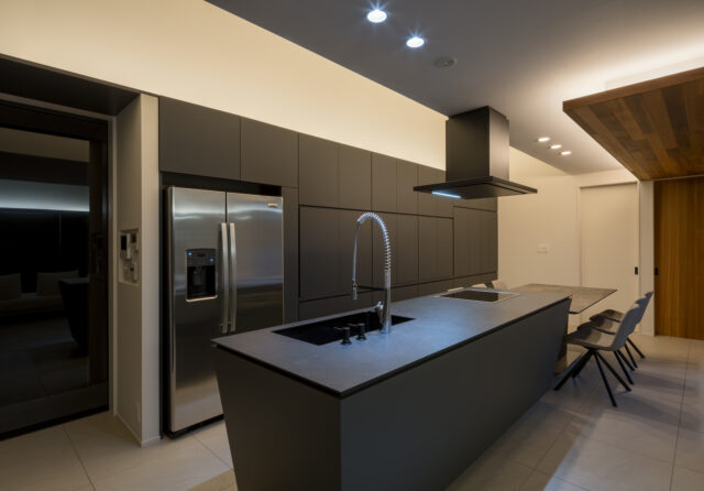 天井高を低くしたキッチンはブラックで統一されたシックな装い。堺さんが設計した収納棚は、使用時に開いた扉が邪魔にならないよう収納できるよう（垂直収納扉）になっているという。