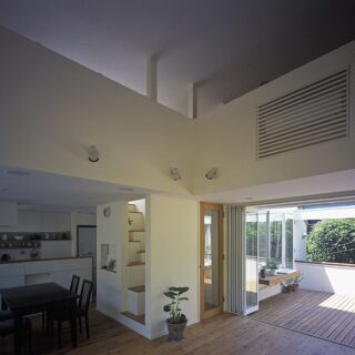 ダイニングとキッチン。造作キッチンで、手元が見えないように配慮している。冷蔵庫・洗剤・調味料など生活感があるものは見えないようにする一方で、見せる収納も意識。キッチン背後に飾り棚を用意した
撮影：石黒 守