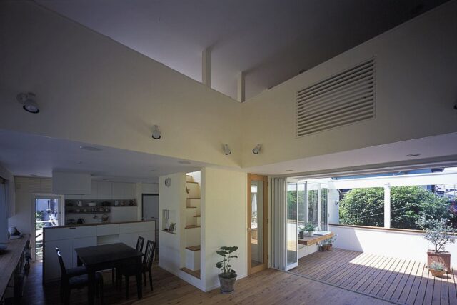 リビング上部は吹き抜けで、3階の部屋の気配も感じられる。テラスとリビングは同じ床材を使用し、アウトドアリビングのような連続性を感じられる開放的な空間だ。一方でダイニングは天井が低く、落ち着く場所となっている。北側の隣家の緑も借景として活用した
撮影：石黒 守